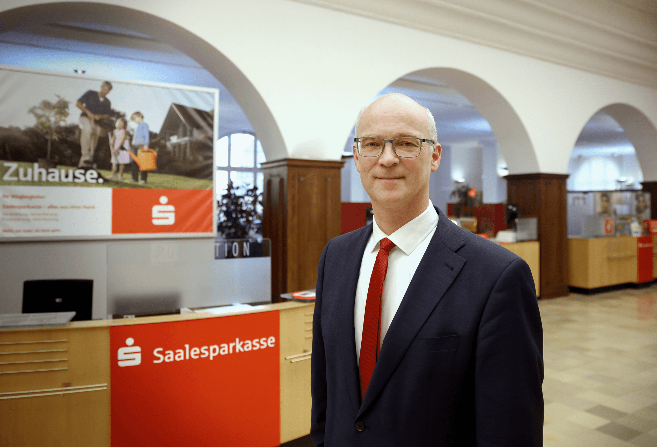 Der Vorstandsvorsitzende der Saalesparkasse in halber Körpergröße in der Bankfiliale fotografiert.